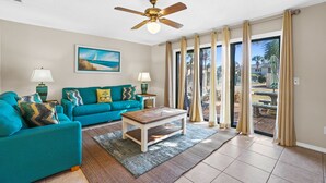 Sala de estar com sofá azul-turquesa, mesa de centro de madeira e ventoinha no teto.