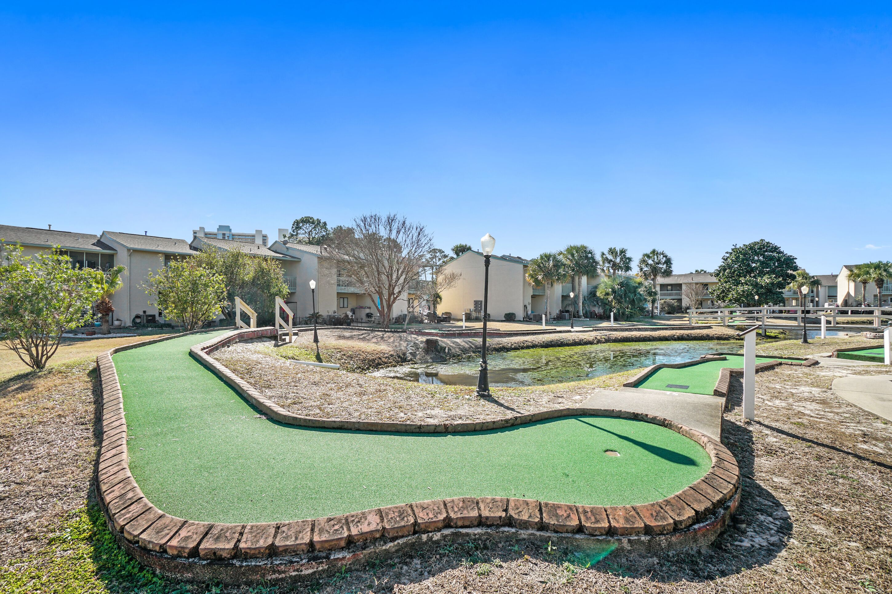 Un parcours de mini-golf doté d’un green, bordé de murets en briques et agrémenté d’un petit étang.