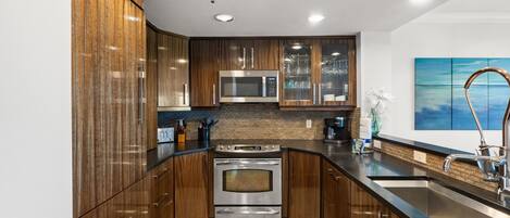 A modern kitchen with wooden cabinets, stainless steel appliances, and a black countertop.