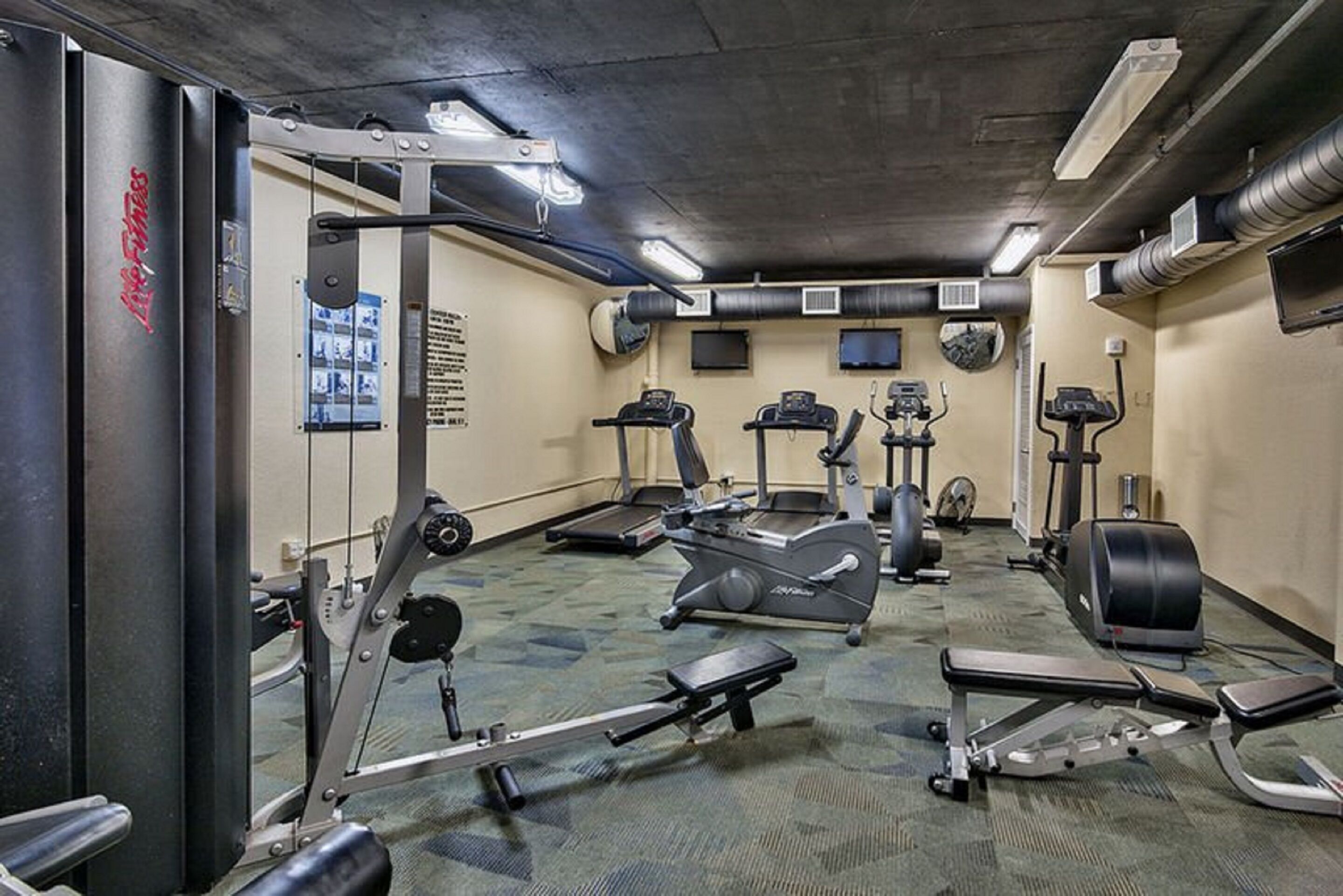 A gym with various exercise equipment including treadmills, elliptical machines, and weight machines.