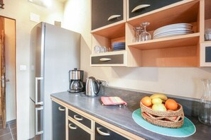 A kitchen with a stainless steel refrigerator, a coffee maker, and a fruit basket on the counter.