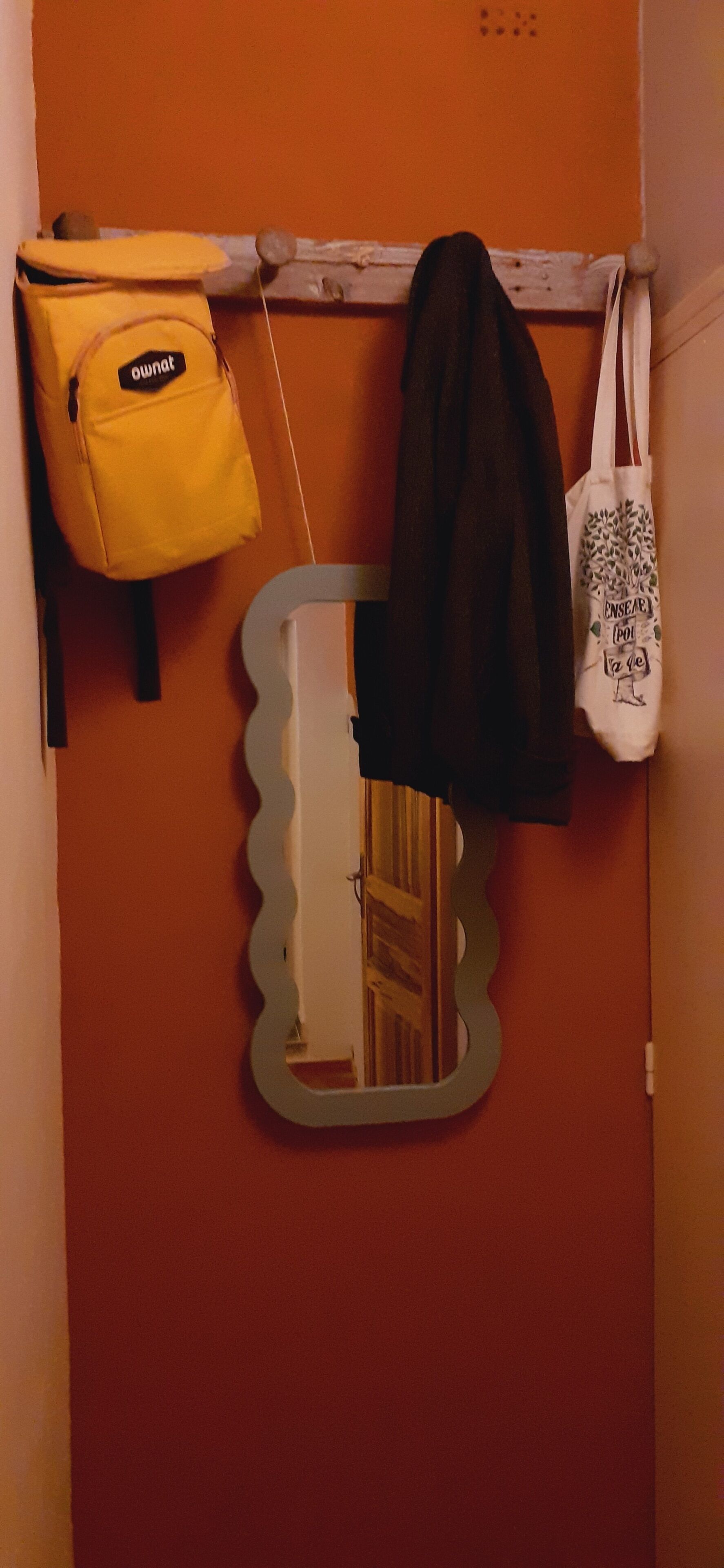 A mirror with a scalloped edge, a yellow bag with the label "ownat," and a white tote bag with a tree design.