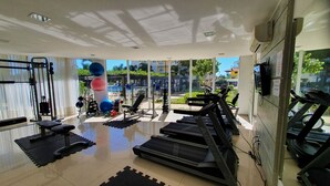 Een sportschool met trainingsapparatuur, een loopband en uitzicht buiten.