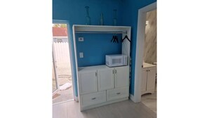 A room with a white wardrobe, a microwave, and a shelf with blue bottles. - Cozy 1 bed in Nassau best kept secret ! (Nassau)