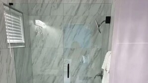 A bathroom with a toilet, a glass-enclosed shower, and a towel rack. - Cozy 1 bed in Nassau best kept secret ! (Nassau)