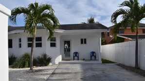 A white house with a porch, two blue chairs, and a gravel driveway. - Elegance & Grace in Nassau contemporary beauty (Nassau)