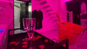 Une pièce avec une table en verre, deux verres à vin et un seau à champagne.