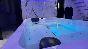Une salle de bain moderne avec un mur en marbre, une baignoire et un escalier.