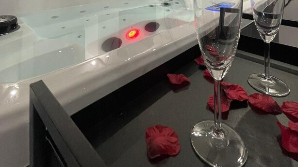Une salle de conférence moderne avec une table en verre, deux verres à vin et des pétales de rose éparpillés sur le sol.