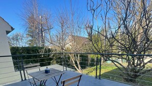 Une terrasse extérieure avec une table et des chaises, entourée d’une clôture en métal et d’arbres.