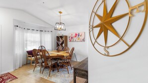 A dining area with a wooden table and chairs, a chandelier, and a decorative compass wall piece. - Pet-Friendly Jupiter Home • Game Room • Central (Jupiter)