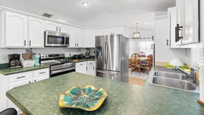 A modern kitchen with white cabinetry, stainless steel appliances, and a green countertop. - Pet-Friendly Jupiter Home • Game Room • Central (Jupiter)