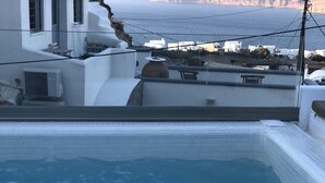 Un bain à remous avec vue sur la mer et les bâtiments blancs en arrière-plan.