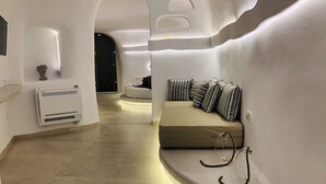 Un intérieur moderne avec un canapé aux lignes courbes, un climatiseur fixé au mur et une bouteille en verre transparent posée sur le sol.