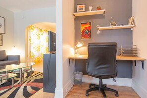 Un soggiorno moderno con un tavolino in vetro, un divano, una TV e una scrivania con una sedia.