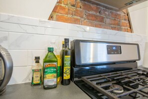 Una cucina con piano cottura a gas, piastrelle di marmo bianco e parete in mattoni.