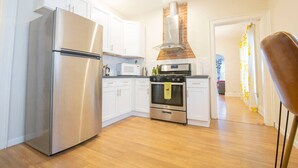 A modern kitchen with stainless steel appliances, white cabinets, and a brick oven. - Elmwood Village 2BR Apt •Sleeps 8• Walk to Dining (Buffalo)