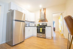 A modern kitchen with stainless steel appliances, white cabinets, and a brick oven. - Elmwood Village 2BR Apt •Sleeps 8• Walk to Dining (Buffalo)