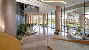 A spacious lobby with a curved staircase, large windows, and a seating area with a unique geometric structure. - Wyndham Garden Cam Ranh Resort (Cam Lam)