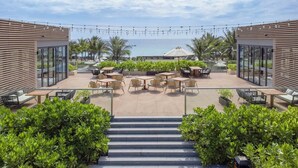 A rooftop patio with outdoor seating, palm trees, and a view of the sea. - Wyndham Garden Cam Ranh Resort (Cam Lam)