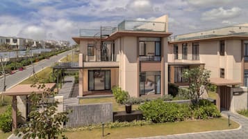 A modern residential building with a two-story structure, a glass balcony, and a paved driveway.
