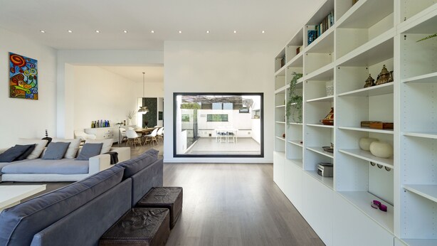 A modern living room with a grey sofa, a white coffee table, and a bookshelf.