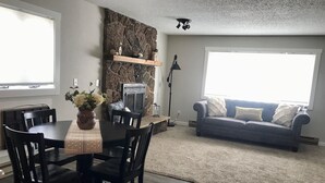 Un comedor con una mesa y sillas, una chimenea, un sofá y un ventanal grande.
