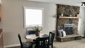 Un comedor con chimenea de piedra, un ventanal grande y una distribución de asientos acogedora.