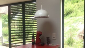 Une cuisine moderne avec un plan de travail rouge, une cuisinière encastrée, une machine à café et une bouteille de vin.