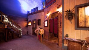 A rustic-themed interior with a wooden staircase, a bar area, and a saloon sign. - Go West- Couples 1-of-a-kind old-time theme-ATL area. (Carroll County)