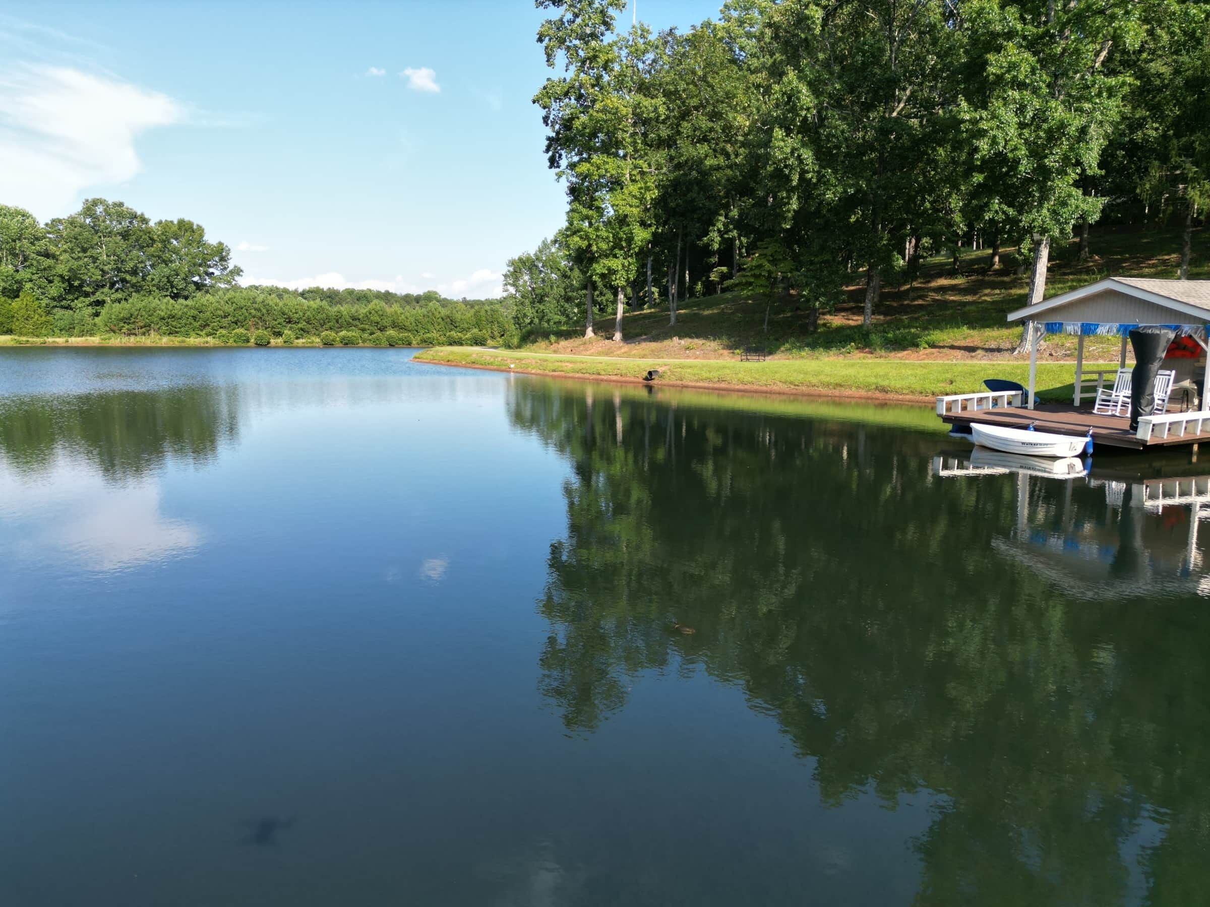 A calm lake with a dock and a covered seating area.