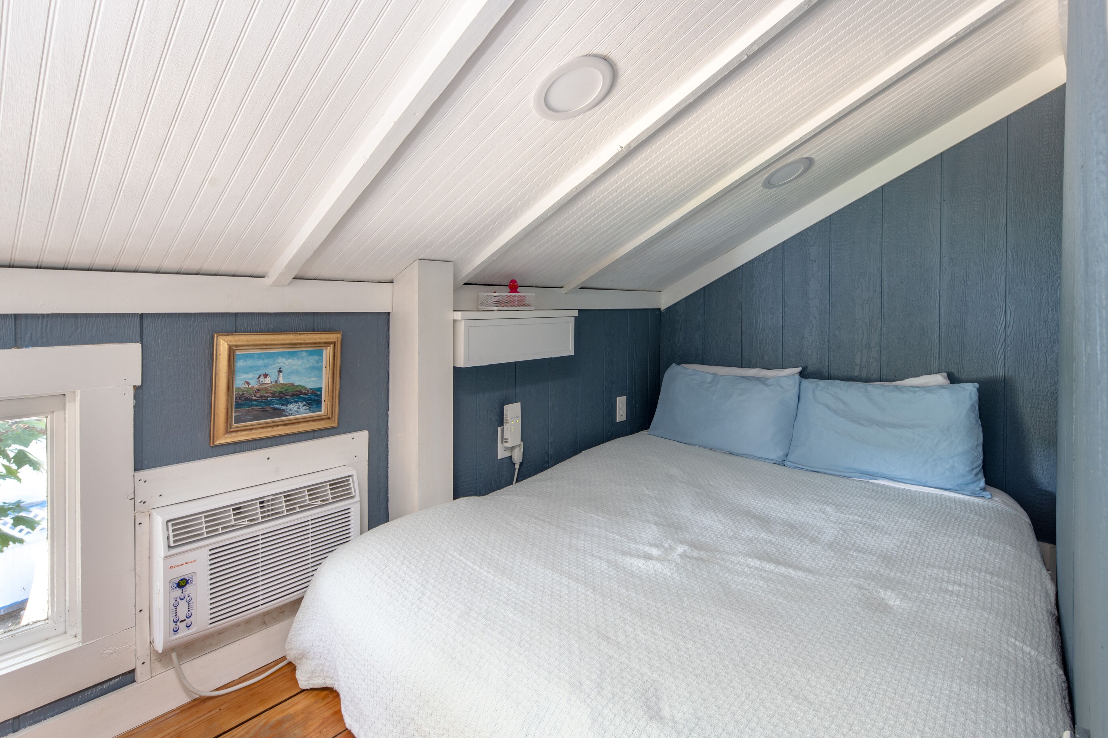 A bedroom with a large bed, a window, and a wall-mounted heater.