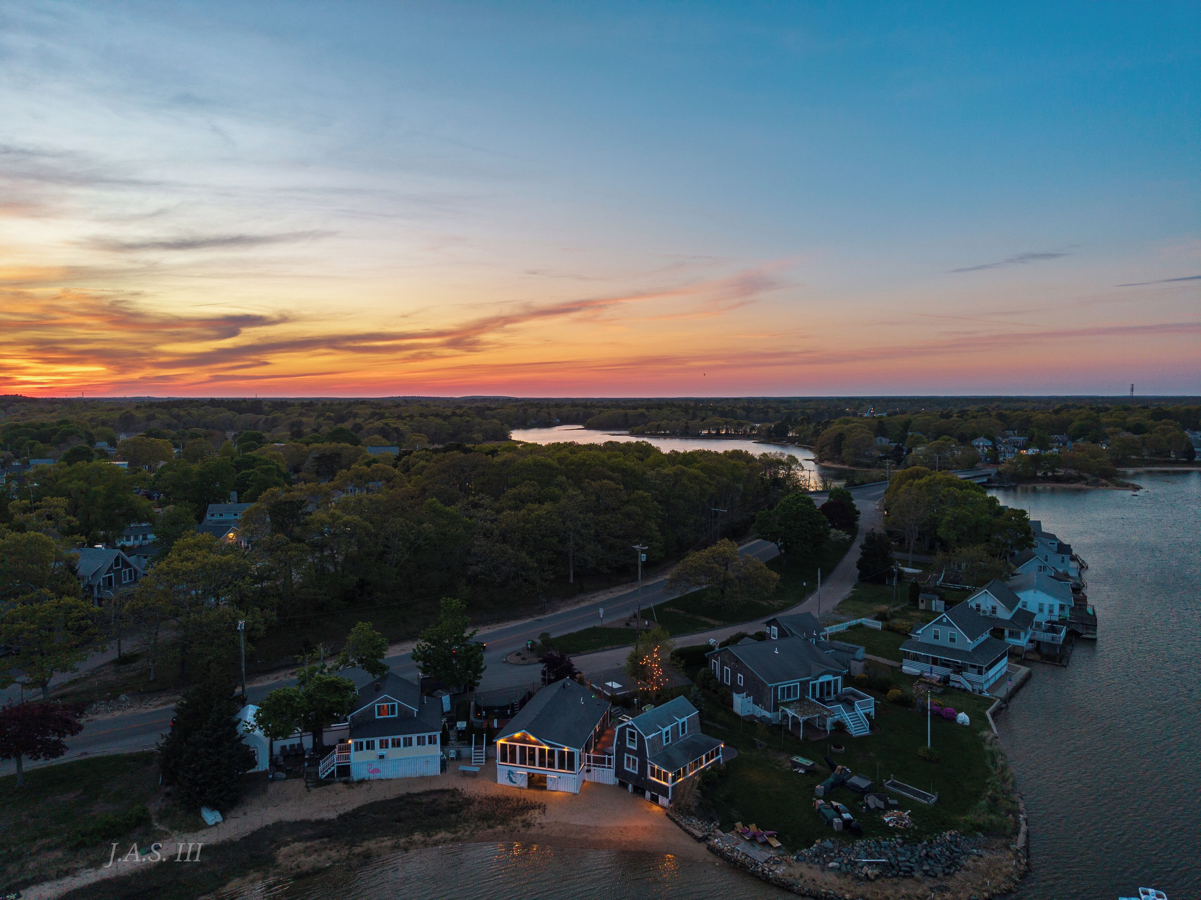 Une zone résidentielle côtière avec des maisons le long de la côte, une route et une rivière en arrière-plan.