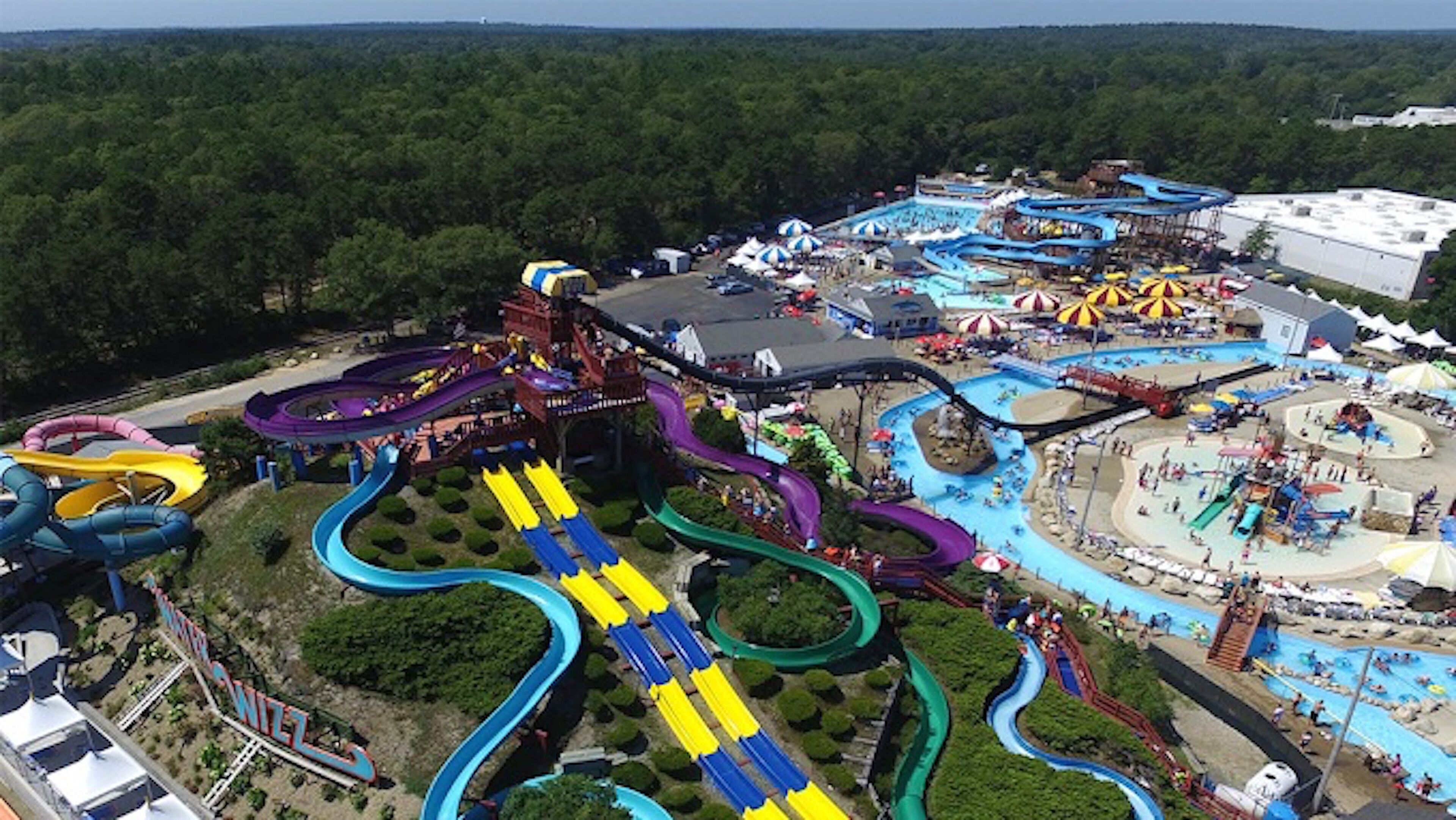 A water park with multiple slides and pools, surrounded by trees.