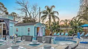 Un espace repas aménagé au bord de la piscine, avec une table pour deux, une petite piscine et des chaises longues.