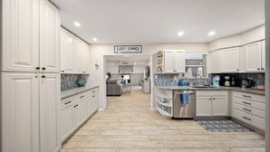 Une cuisine moderne avec des meubles blancs, un sol carrelé à motifs de chevrons et un îlot central.