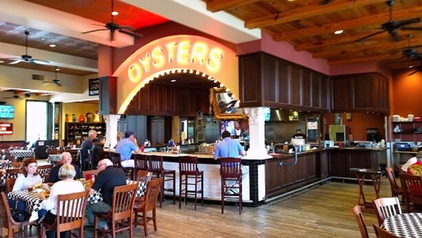 A restaurant interior with a bar area, wooden ceiling, and a neon sign reading "OYSTERS".