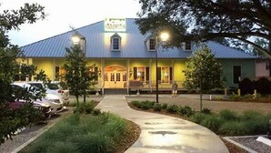 A building with a metal roof, a porch with seating, and a sign above the entrance.