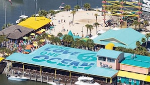 A beachside building with a large sign reading "LOVE ONE OCEAN" and a dock with boats.