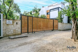 A gated entrance with a stone wall and a wooden fence.