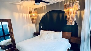 A modern bedroom with a large bed, a ceiling fan, and two hanging light fixtures. - 3 Story Home with Private Roof Pool and Tropical Views (Tulum)