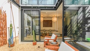 A modern living area with a glass door leading to a balcony, furnished with a sofa, chairs, and a small table. - 3 Story Home with Private Roof Pool and Tropical Views (Tulum)