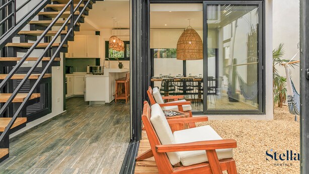 A modern interior with a staircase, a dining area, and a seating area with a view. - 3 Story Home with Private Roof Pool and Tropical Views (Tulum)