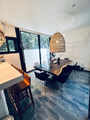 A modern dining area with a large table, chairs, and a hanging light fixture.