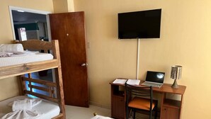Et hotelværelse med køjeseng, et skrivebord med en bærbar computer, et fjernsyn og et klædeskab.