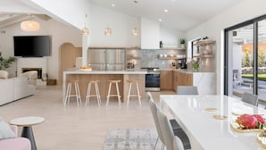 A modern kitchen with a central island, stainless steel appliances, and bar stools. - Solaris - Modern Mediterranean Estate with Pool, Spa and Fire Pit (Palm Springs)