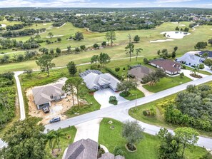 An aerial view of a residential area with houses, roads, and a golf course.