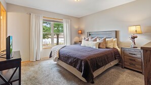 A bedroom with a bed, a nightstand, a lamp, a TV, and a window with curtains. - Lake Front, NEW Sandy Beach, Big Buck Hunter & Pac-Man Arcade Games! Near Nisswa (Pequot Lakes)