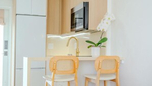 Una cocina moderna con microondas, un lavabo y dos sillas de madera.