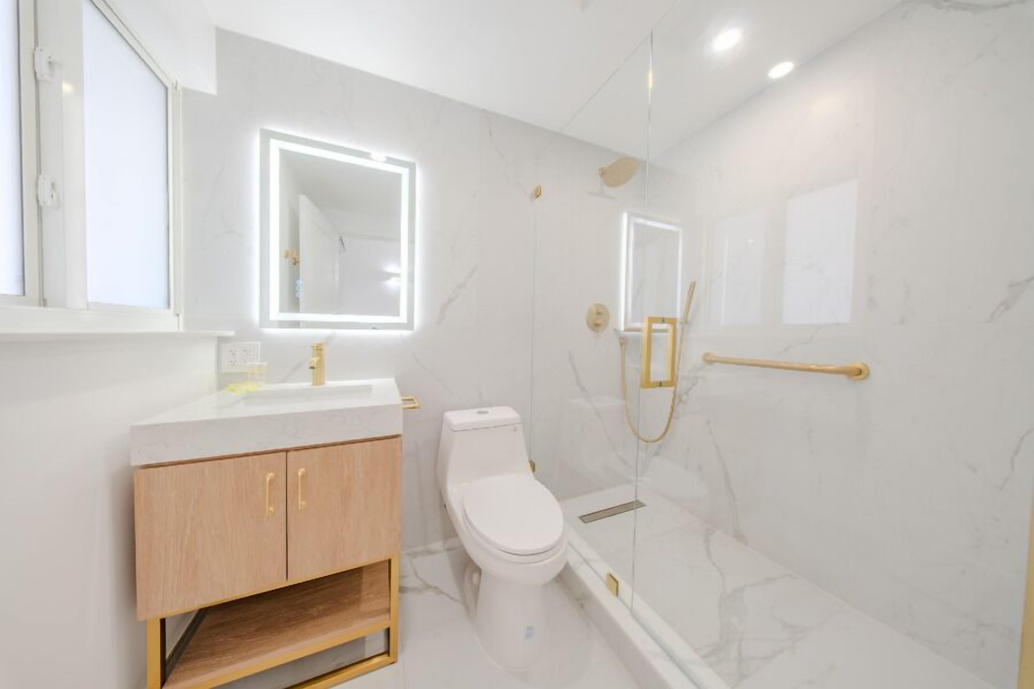 A modern bathroom with a toilet, vanity, and a glass-enclosed shower area.
